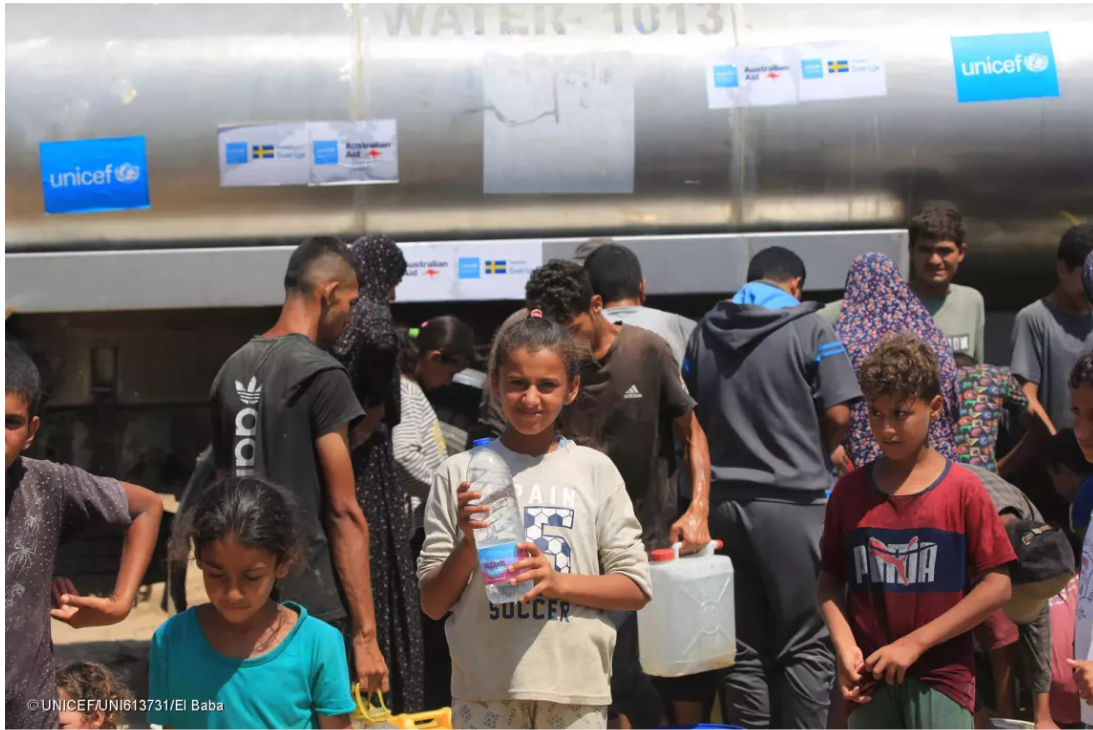 Heba holds a bottle of water after filling it at a UNICEF-supported water tank.