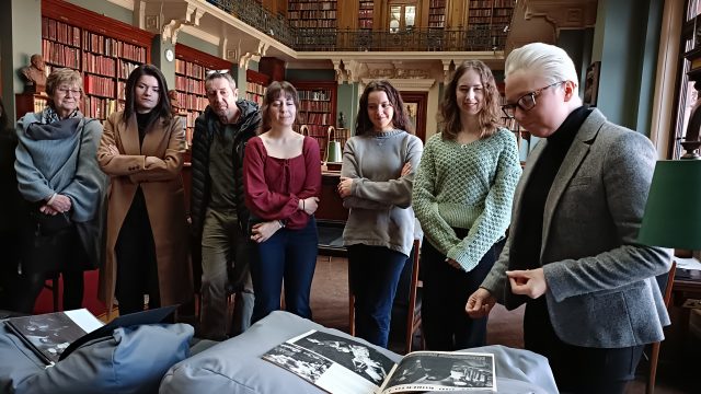 Librarian showing a book to a group of visitors.