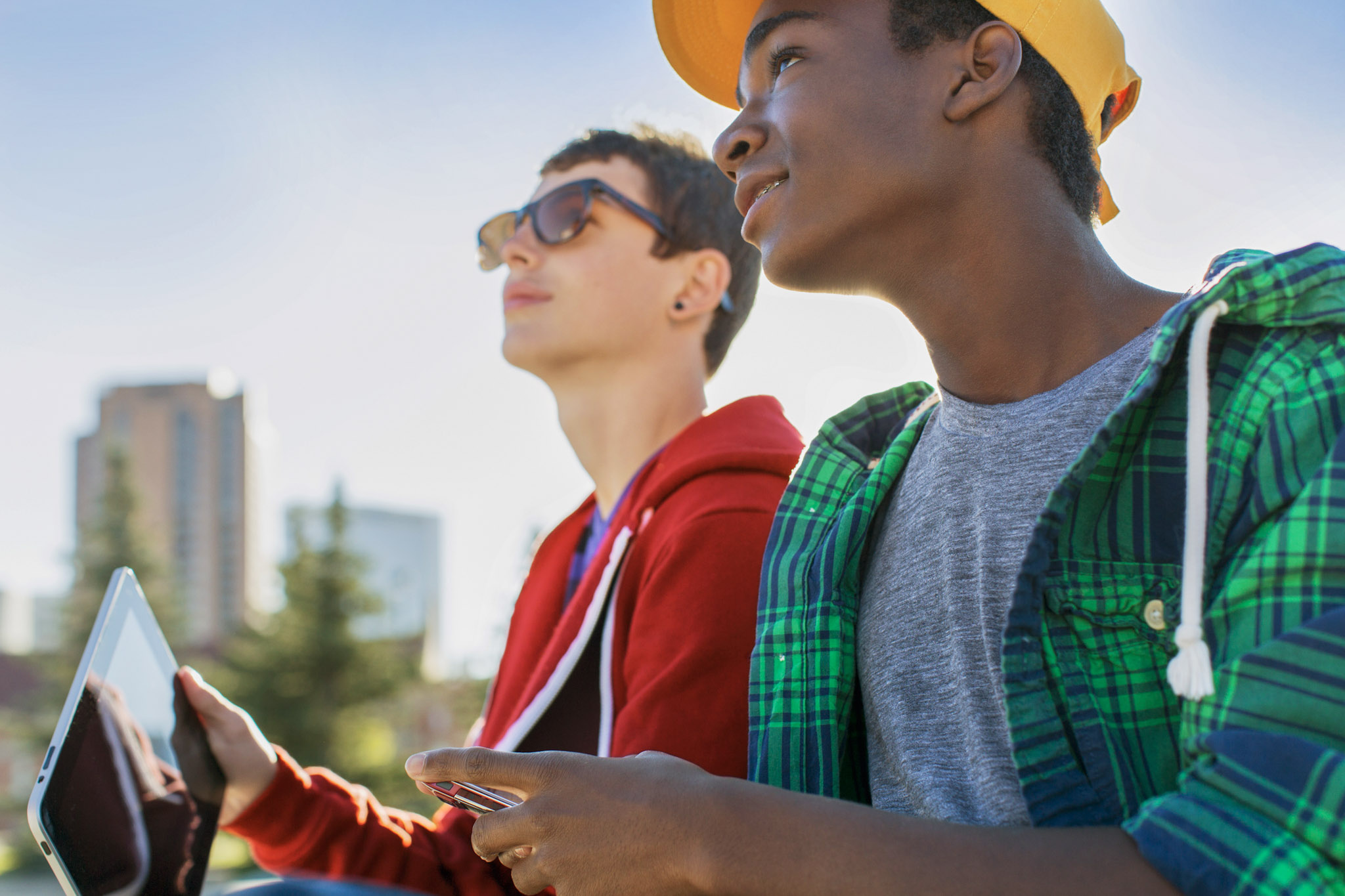 stock photo of two teenage boys outside with a smartphone and a tablet