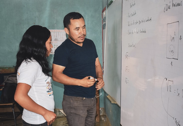 Digna and her teacher Fredy work on a math problem on the whiteboard during class. World Vision staff and U.S. government aid allowed Digna to avoid child labor in Honduras, and instead continue her education and dream of becoming a teacher in the future!