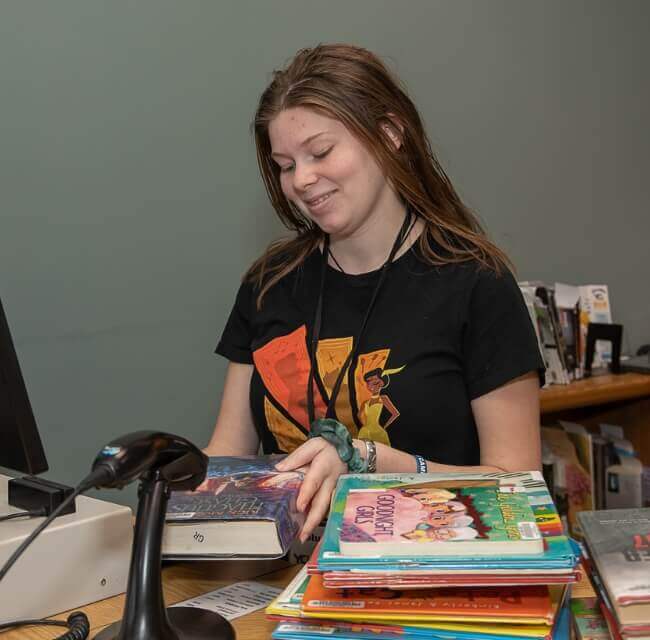 Teen Volunteer Checking In Books At Arthur Hufnagel Library