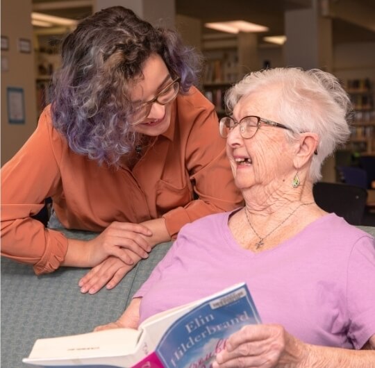 Younger And Older Woman Smiling While Discussing A Book At Glatfelter Library