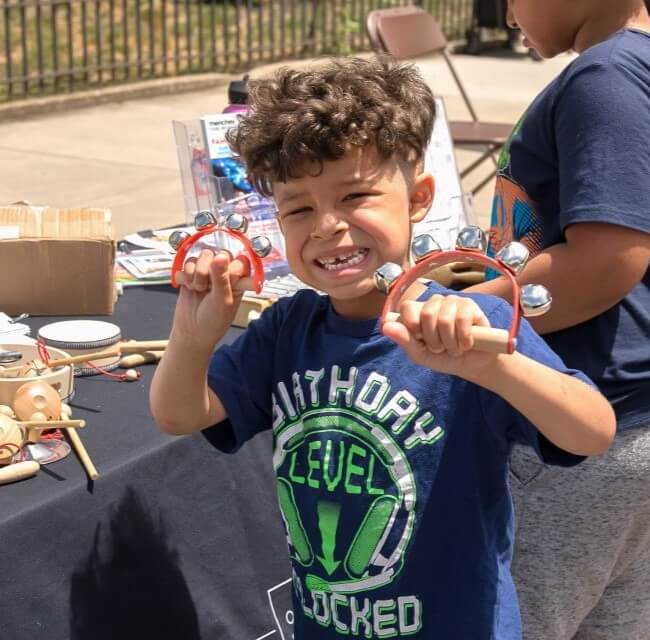 Child Shaking Jingle Bells At Block Party