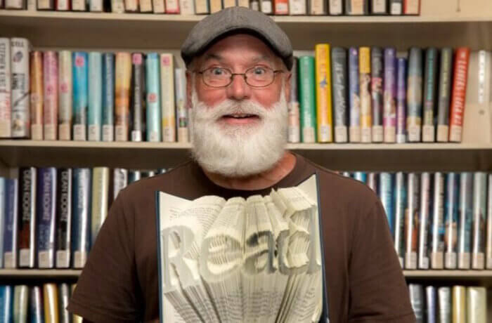 Older Man Holding Folded Pages Book